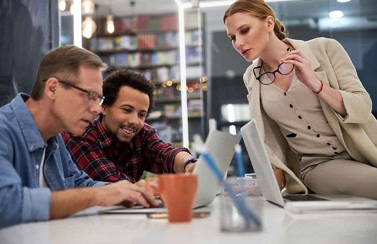 Three people looking at laptop
