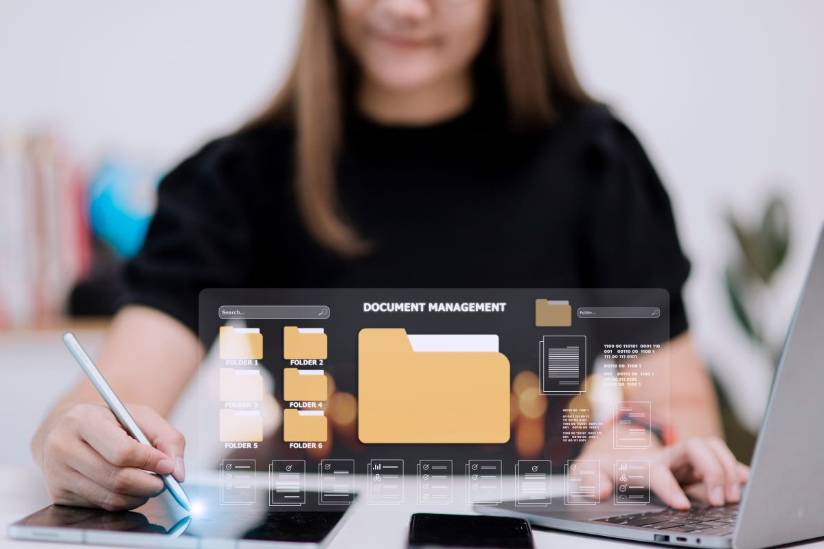 Woman holding a tablet pen over a tablet with an illustration of computer folders over the tablet