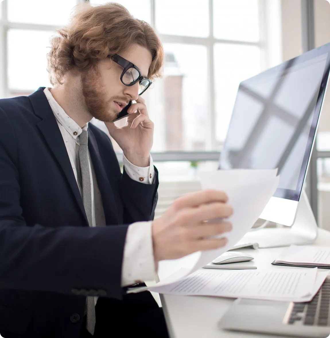 A professional man wearing glasses and a suit talks on his phone