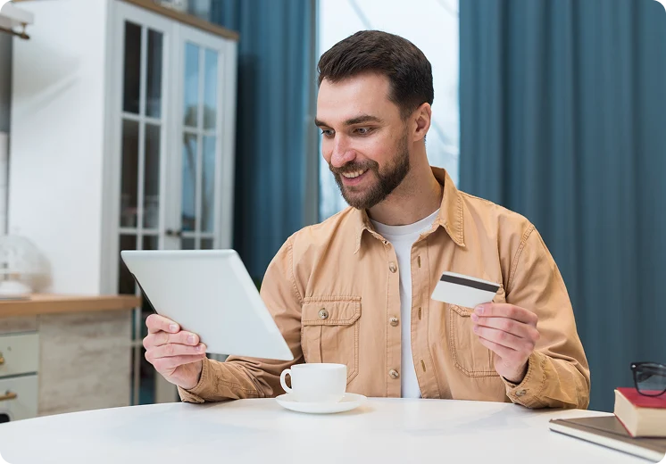Smiling man holding a tablet and a credit card
