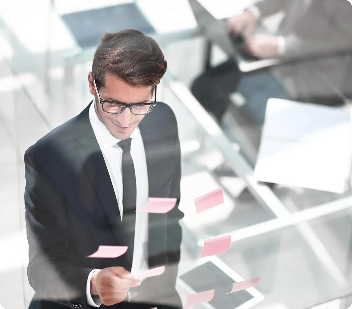 A professional man in a suit and glasses looking at sticky notes